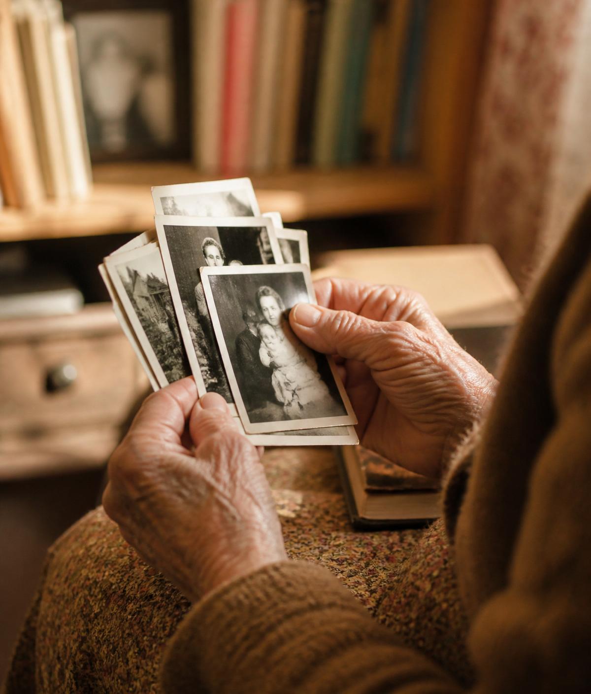 Manos de una persona mayor sosteniendo fotografías antiguas